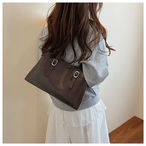 Detail view of the dark brown leather shoulder bag on model in a minimalist room