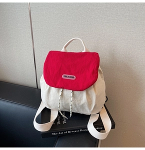 Detail of red and cream backpack showing drawstring closure and brand logo flap