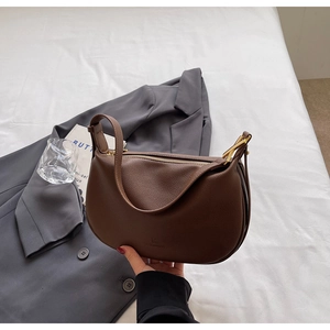Detail of dark brown crescent bag with lychee texture and gold-toned zipper hardware