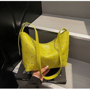Close-up of vibrant lime green leather dumpling bag with silver rivet studs and fine strap
