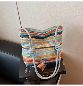 Gros plan d'un sac seau tissé multicolore avec lanières en cuir bleu et logo de marque