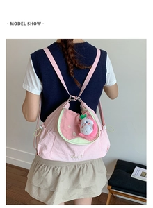Détail du sac à dos en toile rose goyave avec pendentif fruit en peluche et broderie
