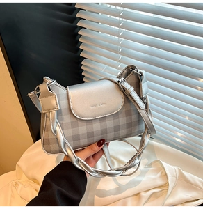 Detail of silver checkered crossbody bag with metallic flap and stylish woven handle