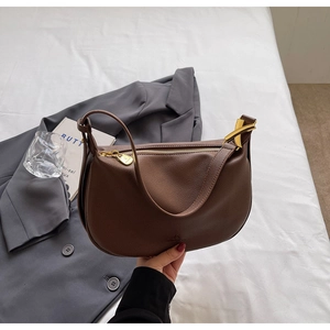 Detail of dark brown lychee textured hobo bag with elegant gold zipper and metal accents