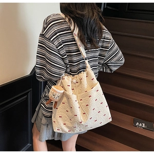 Detail of cream canvas bucket bag with red bows and cute toast plush charm