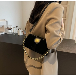 Close-up of black matte doctor bag with gold emblem and thick chain detail on a model