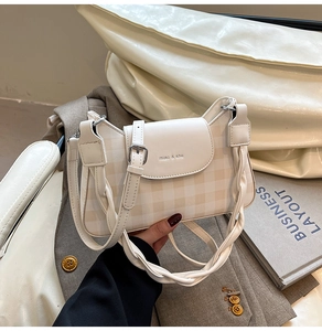 Detail of checkered beige and brown crossbody bag featuring a thick woven shoulder strap