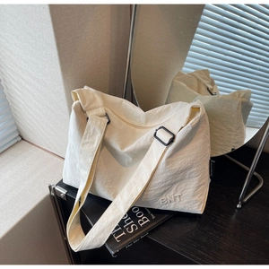 Détail du sac bandoulière crème avec sangle réglable et broderie du logo BNT élégante