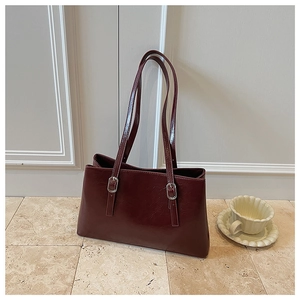 Detail of dark burgundy oil wax leather shoulder bag with elegant silver metal buckles