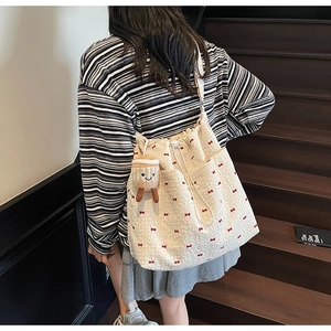 Detail of canvas bucket bag with red bow pattern and cute smiling coffee cup charm