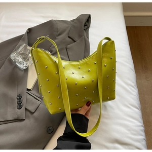 Detail of lime green shoulder bag featuring silver rivets and metallic buckle strap