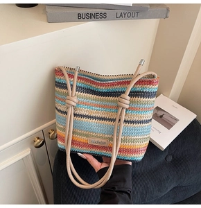 Détail du sac seau en paille tissée multicolore avec logo et bandoulière à nœuds