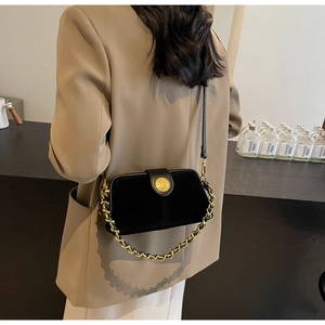 Close-up of black velvet shoulder bag with gold chain strap and metal buckle detail