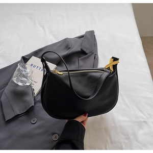 Detail of black pebbled leather hobo bag with gold metal zipper and X-shaped buckle