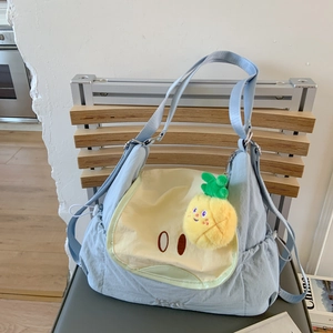 Détail du sac en nylon bleu clair avec rabat beige brodé et pendentif ananas mignon