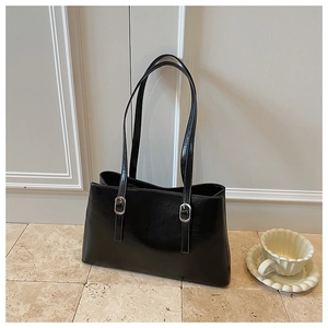 Detail of black glossy leather tote bag with silver buckles and fine texture
