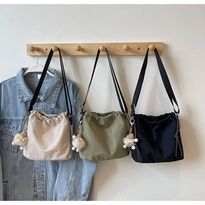 Détail de sacs seaux légers en blanc, olive et noir avec des pendentifs en peluche