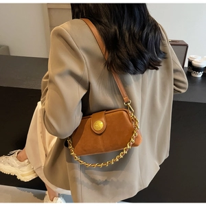 Detail of vintage brown suede crossbody bag with gold chain and embossed emblem