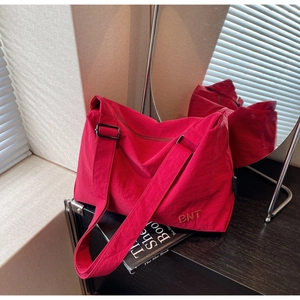 Détail d'un sac fourre-tout rouge en nylon avec broderie BNT et bandoulière réglable