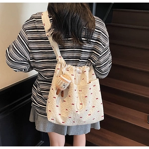 Detail of off-white mesh shoulder bag with red bow embroidery and drawstring closure