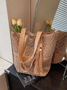 Summer woven straw tote bag with tassel charm and hollow pattern for beach vacations