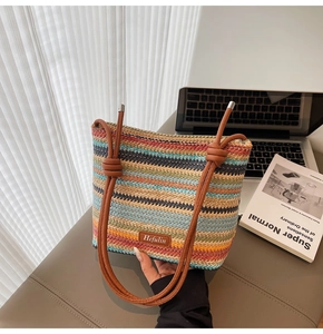 Détail d'un sac seau tissé à rayures colorées avec bandoulière en similicuir marron