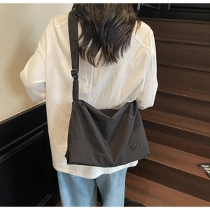 Close-up of black waterproof nylon crossbody bag with BNT logo on a female model