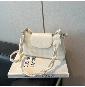 Detail view of cream checkered crossbody bag with braided strap and logo texture