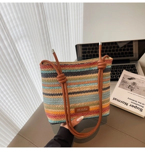 Détail du sac seau tissé à rayures multicolores avec bandoulière en cuir marron et logo