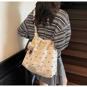 Detail of off-white tote bag with red bow embroidery and a cute hamburger plush charm