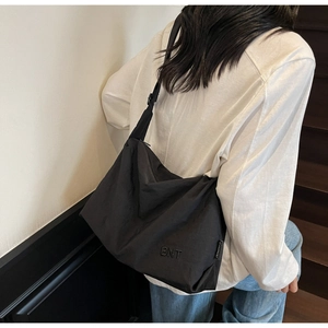 Detail of black nylon crossbody bag with BNT embroidery on a model in urban setting