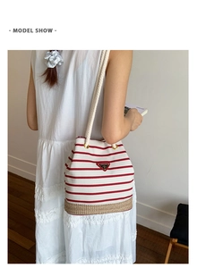Modella che indossa una borsa a secchiello a righe rosse con base in paglia intrecciata