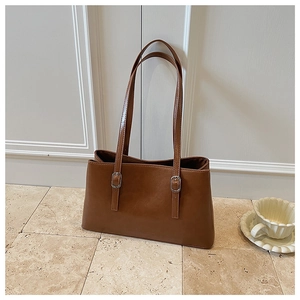 Detailed texture of brown leather tote bag with silver buckle on the shoulder strap