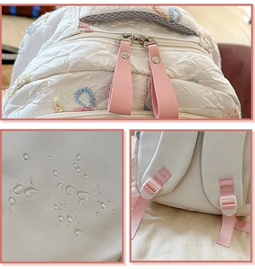 Waterproof detail of white quilted backpack featuring colorful wavy embroidery and pink straps