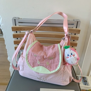 Détail du sac bandoulière pastèque rose avec broderie de pépins et pendentif peluche