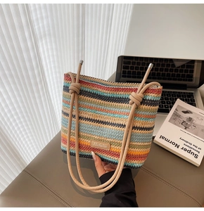 Détail d'un sac seau tissé à rayures arc-en-ciel avec un écusson en cuir et des anses nouées