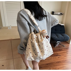 Close-up detail of cream waffle fabric shoulder bag with red bow print and plush charm