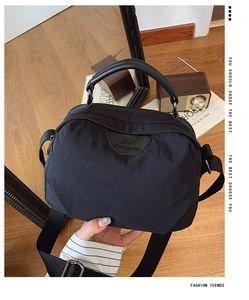 Dettaglio della borsa a tracolla in nylon nero con logo in pelle e ampia tracolla