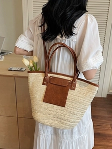 Chic woven straw tote bag with brown leather handles and decorative front pocket