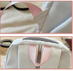 Detailed view of pink handles and reinforced nylon stitching on a white quilted backpack