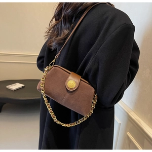 Detail of dark brown suede doctor bag with gold emblem buckle and chain strap