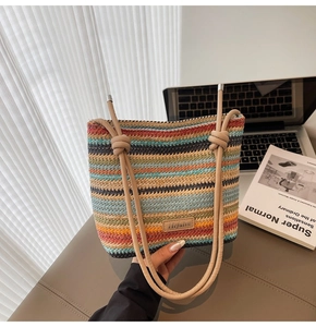Gros plan du sac seau tissé à rayures colorées avec étiquette en cuir sur bureau