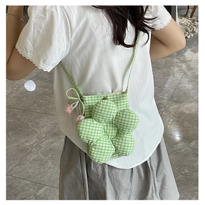 Detail of green and white plaid flower bucket bag with floral charm on model