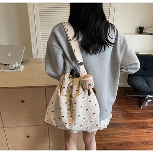 Close-up of beige bow-print bucket bag with a cute cupcake plush charm on a model