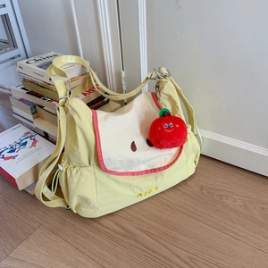 Détail de la broderie pomme sur sac bandoulière en nylon jaune clair avec charm pelucheux