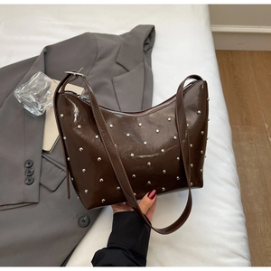 Detail of dark brown glossy leather hobo bag with silver metallic stud embellishments