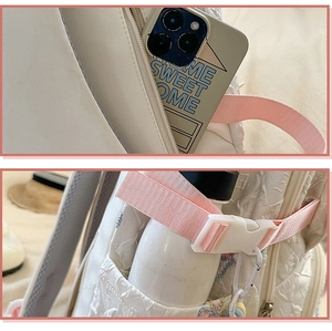 Detail of white quilted backpack with pink side buckle strap and zipper pockets