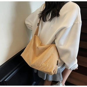 Close-up of a cream nylon shoulder bag with pleated texture and BNT embroidery detail