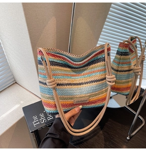 Détail d'un sac seau tissé à rayures colorées avec anses en corde et logo discret