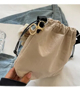 Gros plan détaillé d'un sac seau beige avec cordon de serrage et bandoulière tissée